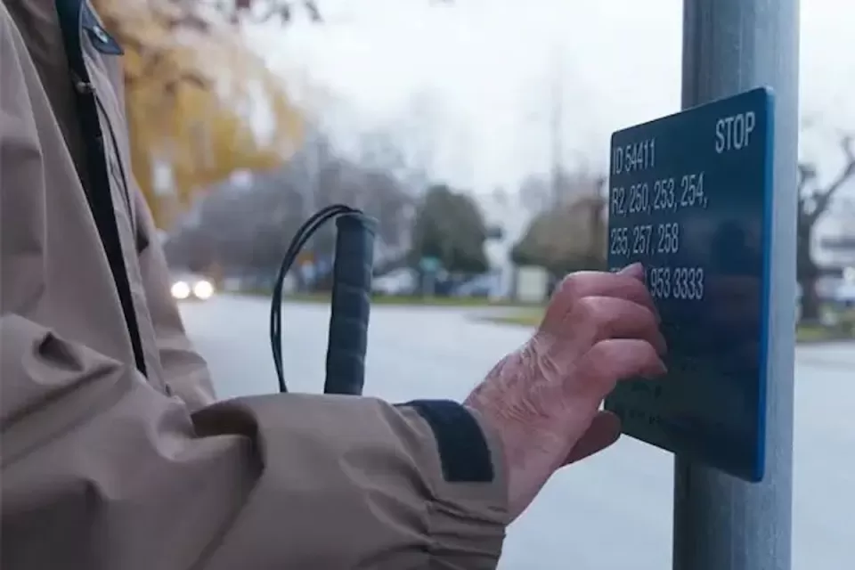Close-up of hand reading Braille sign at bus stop in Vancouver, British Columbia.